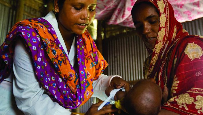 JiVitA interviewer Ripu Rani measures a child's arm while her mother looks on