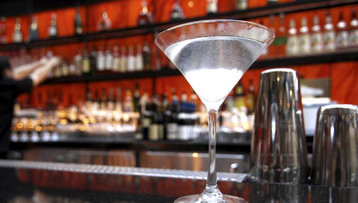 a martini on a bar next to a cocktail shaker