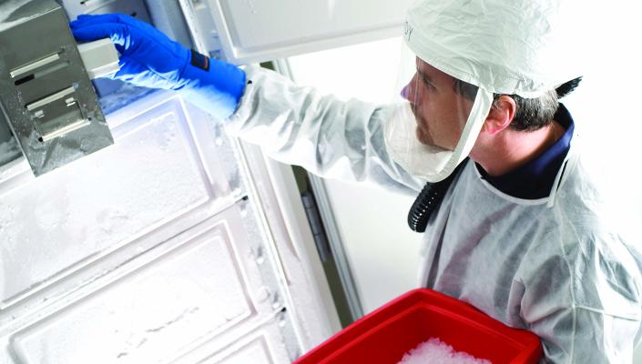 Andy Pekosz, in hazmat gear, removes a sample from a freezer