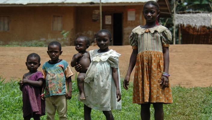 4 children standing in line youngest to oldest; one child holds a toddler on her hip.