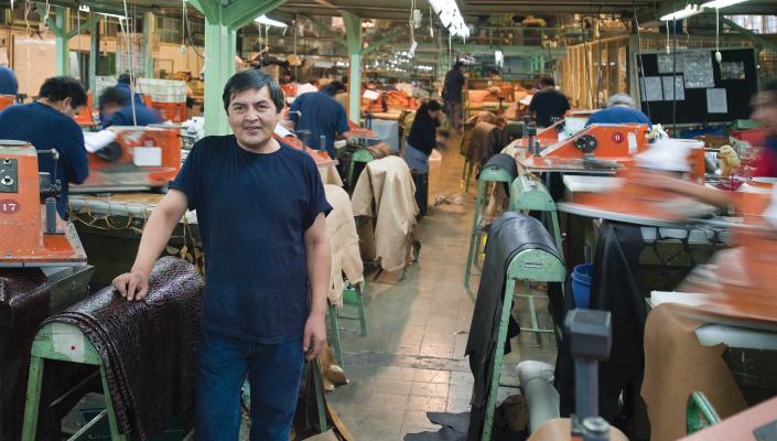 A man stands on a busy textile plant workroom floor.