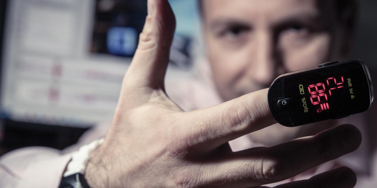 closeup of a man's hand with a pulse oximeter on one finger