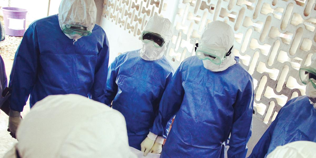 4 researchers wearing blue PPE and goggles