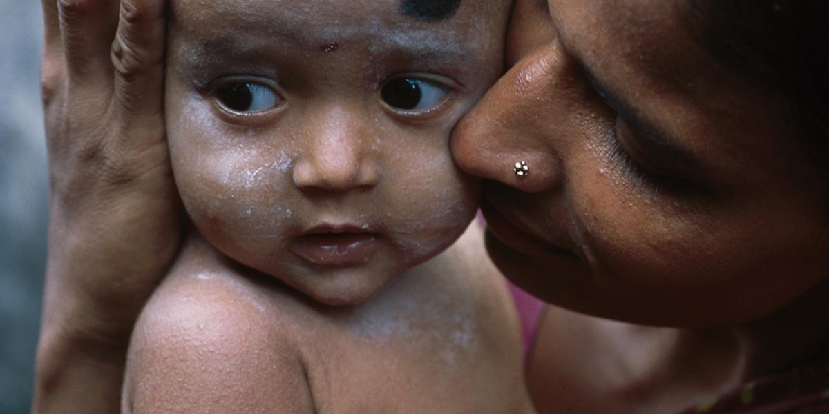 a mother holds and kisses the cheek of her infant