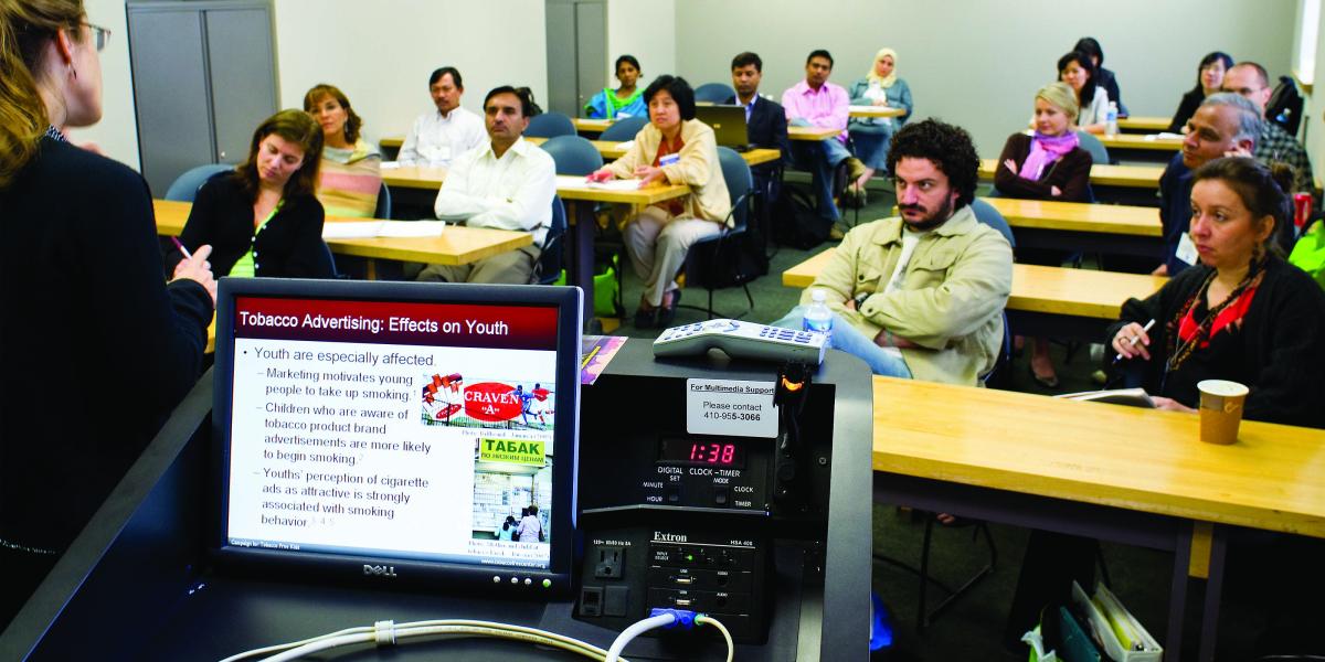 Students in a classroom listen to a talk on Tobacco Advertising: Effects on Youth, which is visible on the presenter's laptop monitor