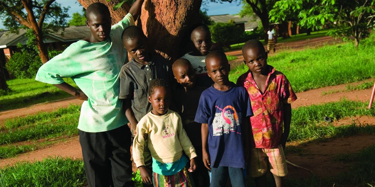 a man and 6 children stand in the shade of a tree in Macha, Zambia