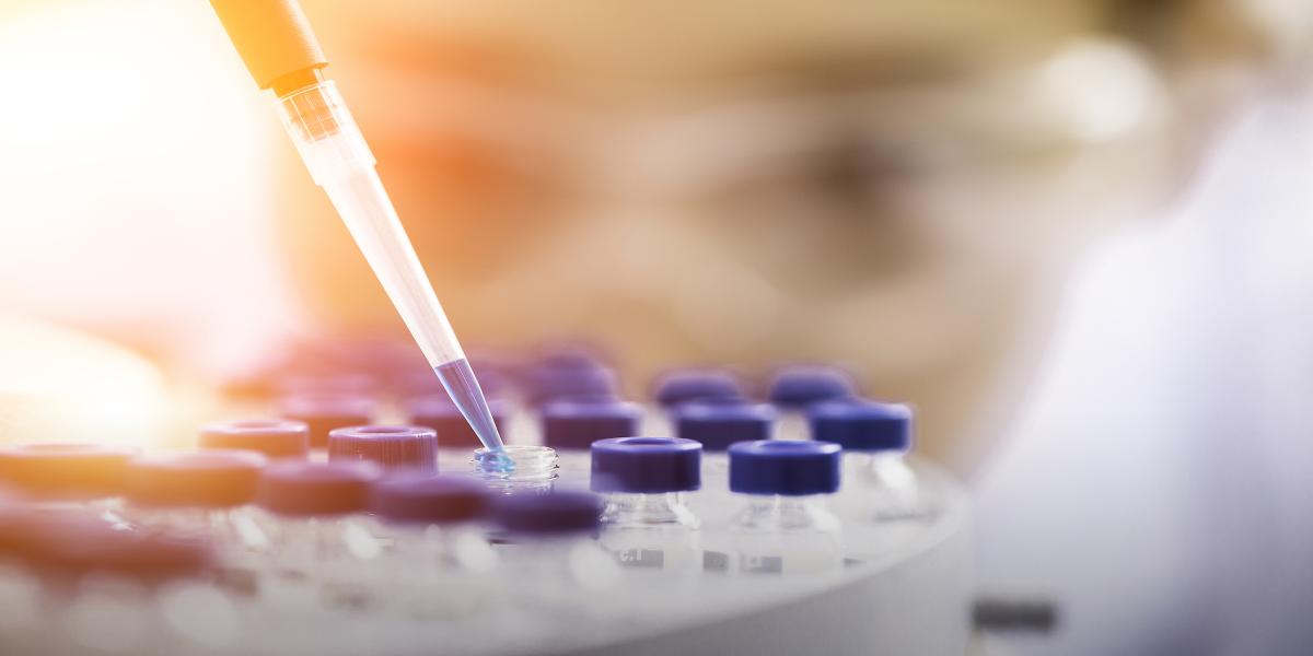 photograph of scientist wearing goggles pipetting liquid into vials