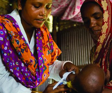 JiVitA interviewer Ripu Rani measures a child's arm while her mother looks on