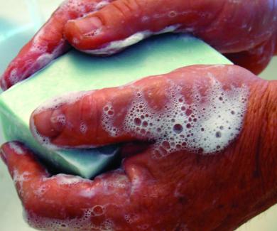 close-up of two lathered hands with a bar of green soap