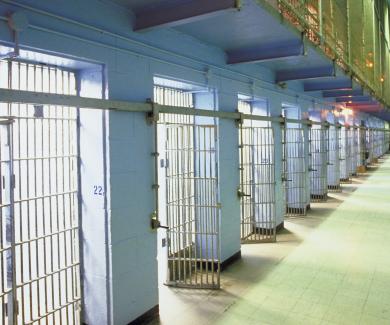 an interior photo of a jail, looking down a long row of cells