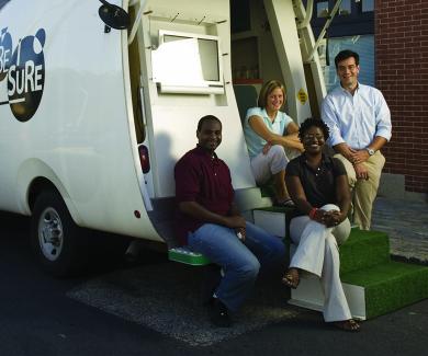 McCay Morifay, Martha Hilton, Frangiscos Sifakis, and Keba Robinson sit and stand at the back of the BESURE van.