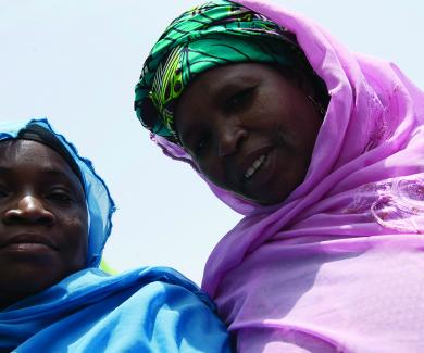 2 Nigerian women, one in a blue scarf and the other in pink